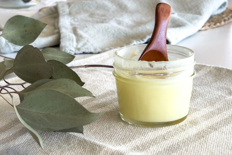 jar of diy face moisturizer sits on the counter with a small wooden spoon in it