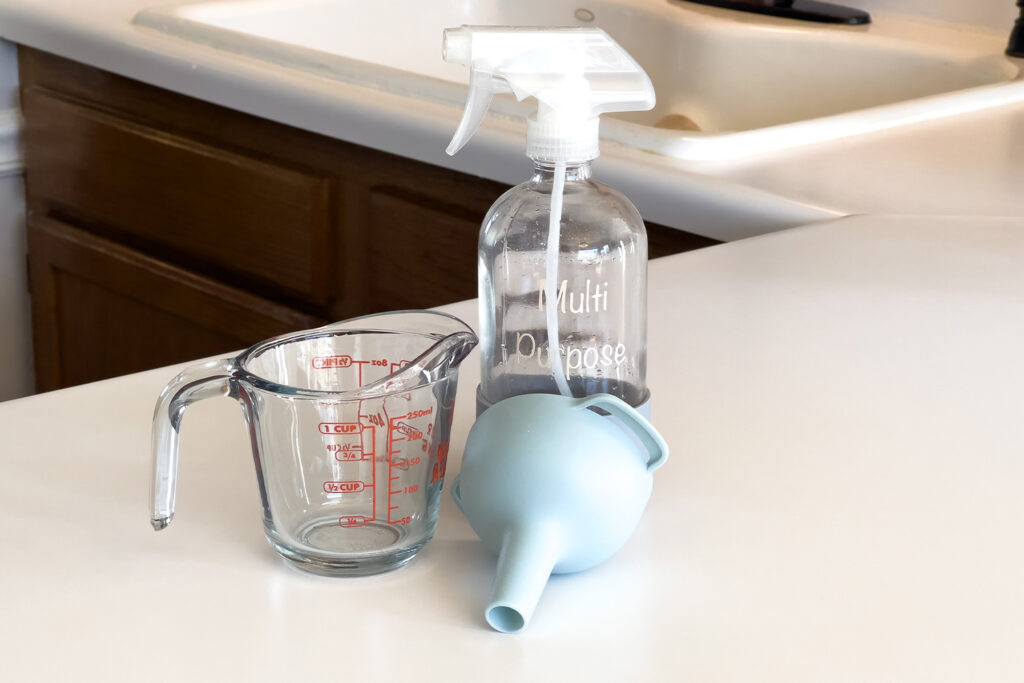 a spray bottle, a measuring cup, and a funnel, for how to make a multi purpose cleaning spray