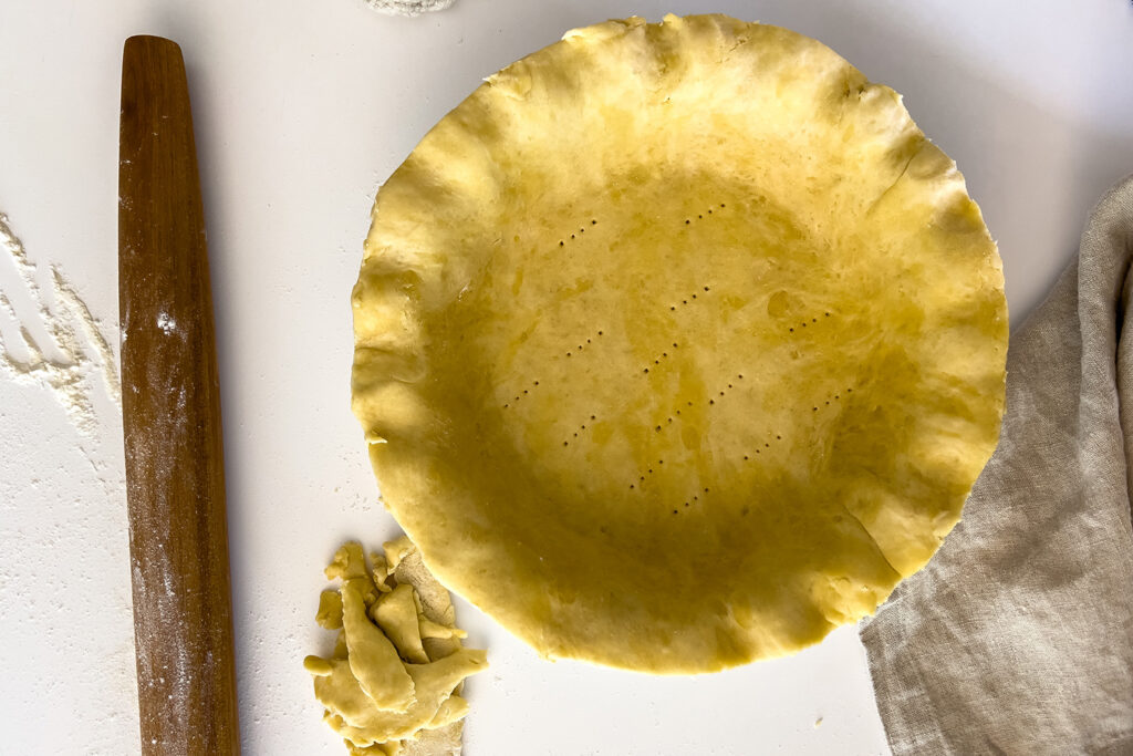 a pie plate with excess dough sits on the counter