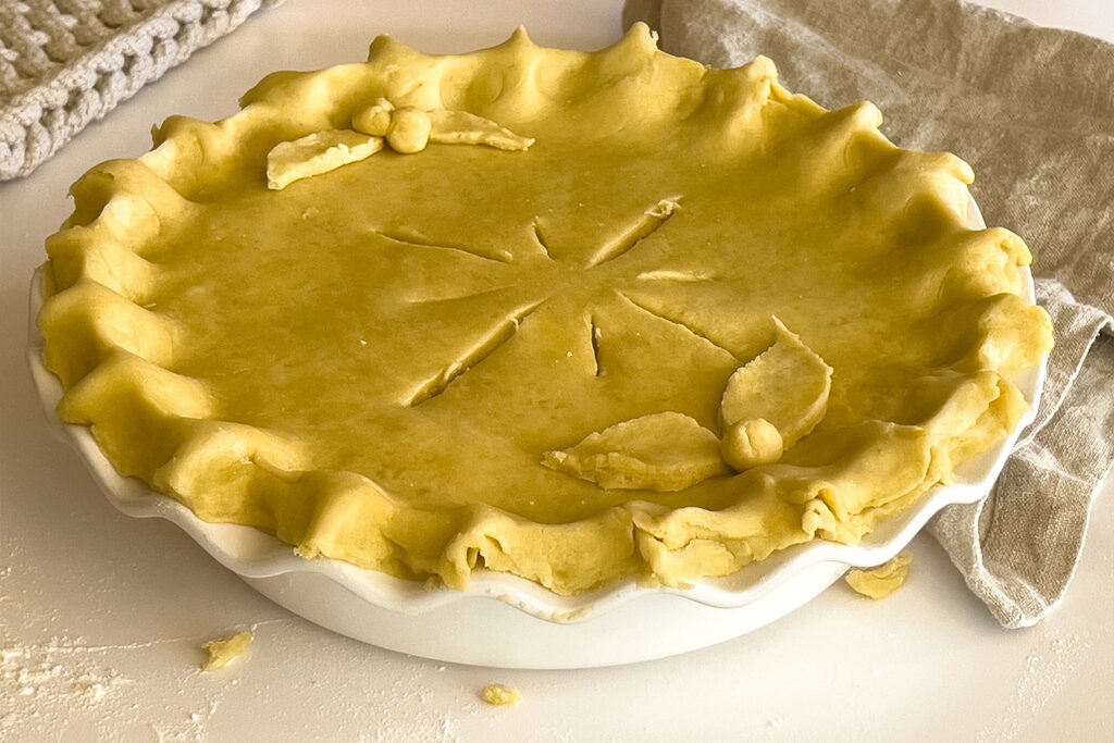 an unbaked pie with a leaf pattern sits on the counter