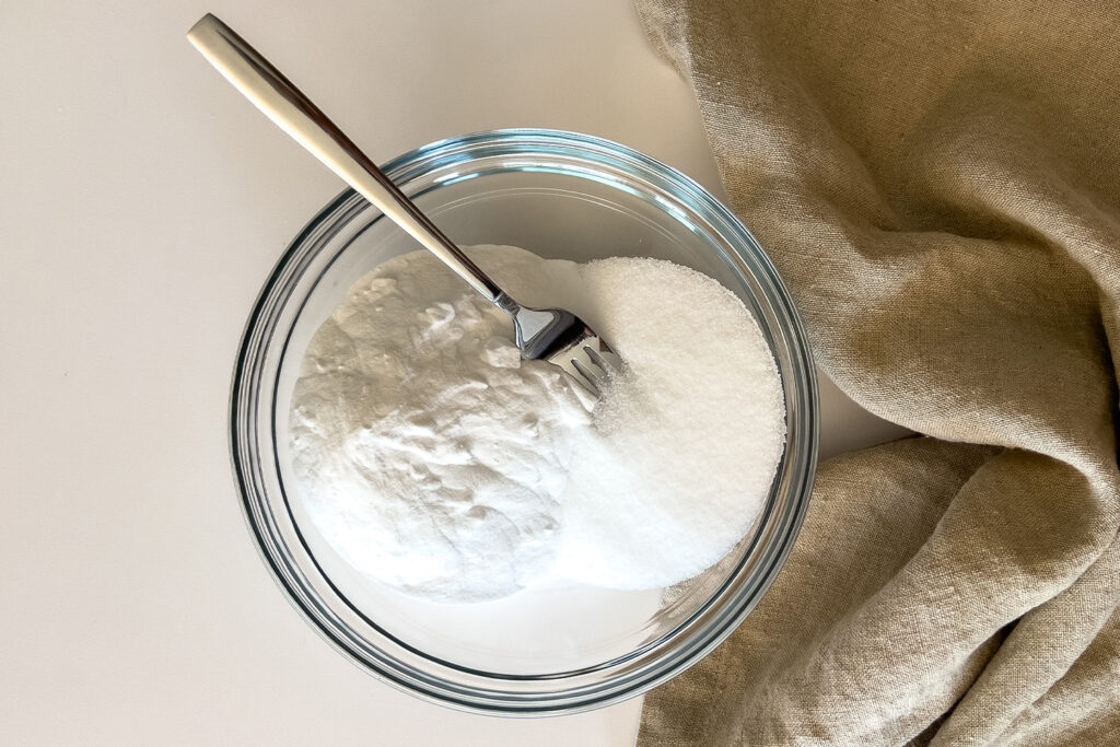 a bowl of baking soda and salt sits on the counter with a fork in it
