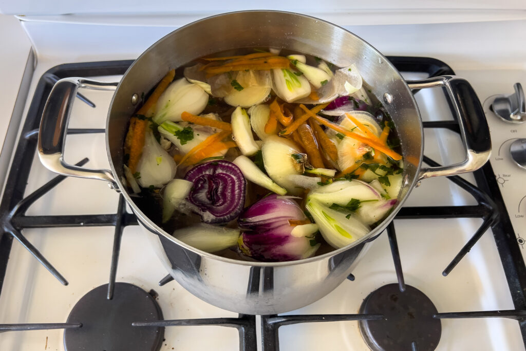 a stockpot with vegetables, bones, and water sits on the stove