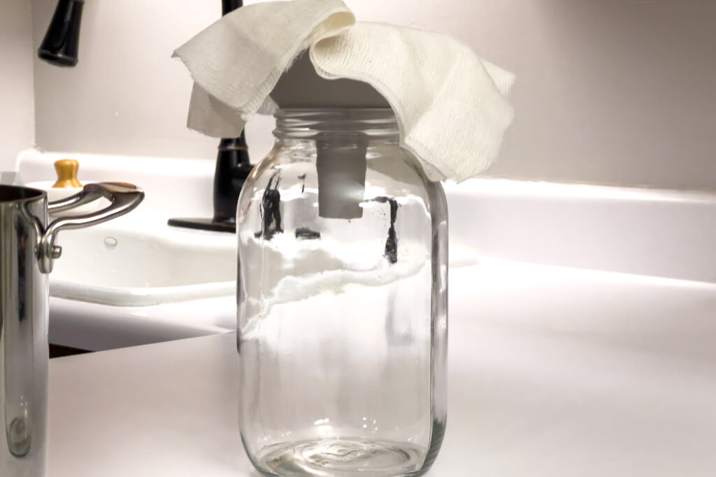 a cheesecloth is in a funnel in a jar