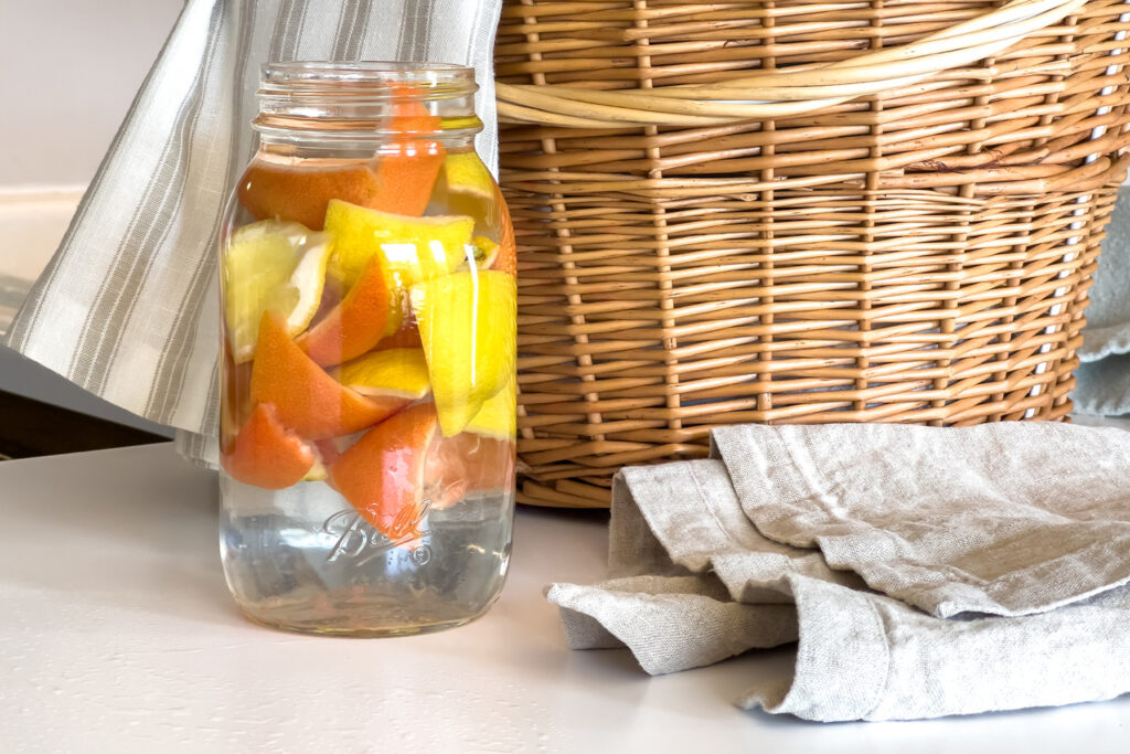 a jar of vinegar filled with citrus peels sits on the counter