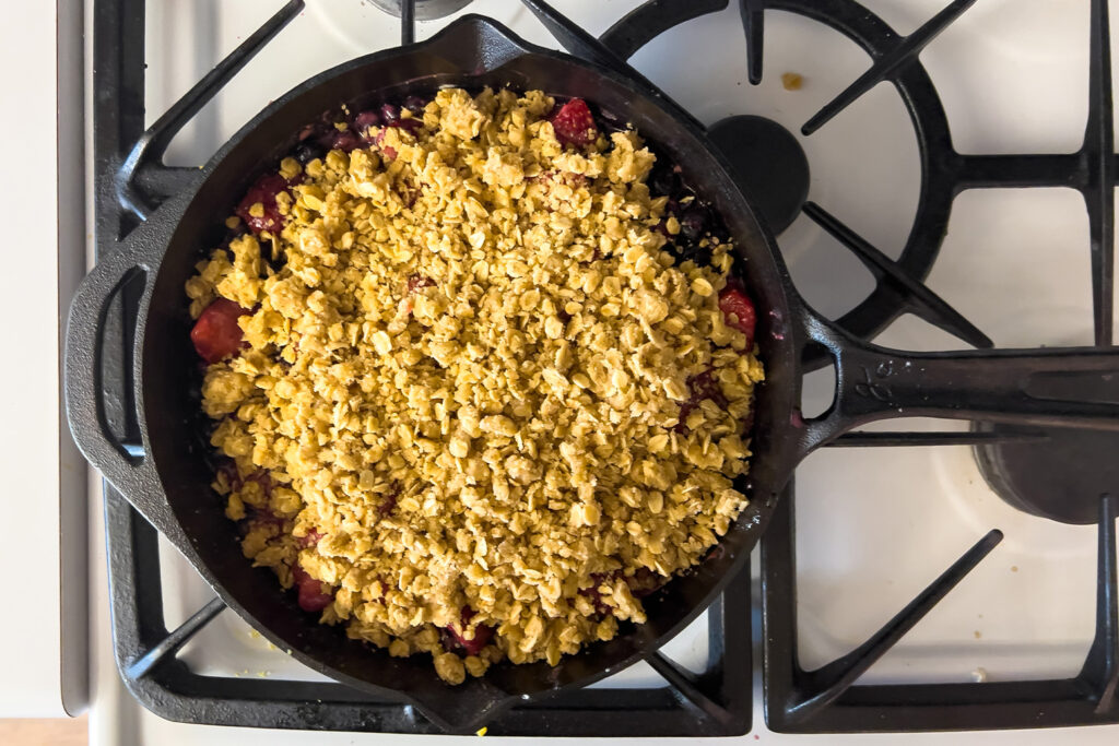 a cast iron skilled full of lemon berry crumble is sitting on the stovetop ready to bake