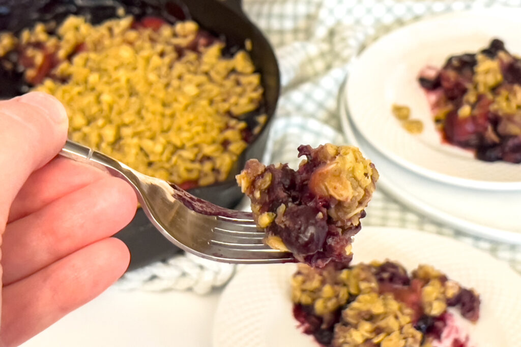 a bite of lemon berry crumble is sitting on the tip of a fork ready to be eaten
