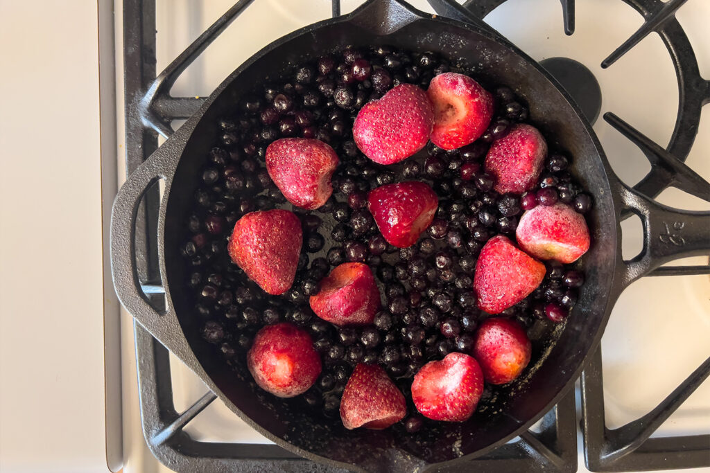 a cast iron skillet is filled with strawberries and blueberries