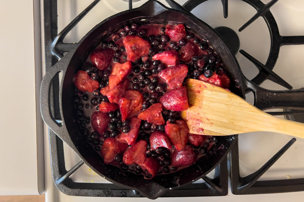 the berries in a cast iron skillet are being broken apart by a wooden spatula