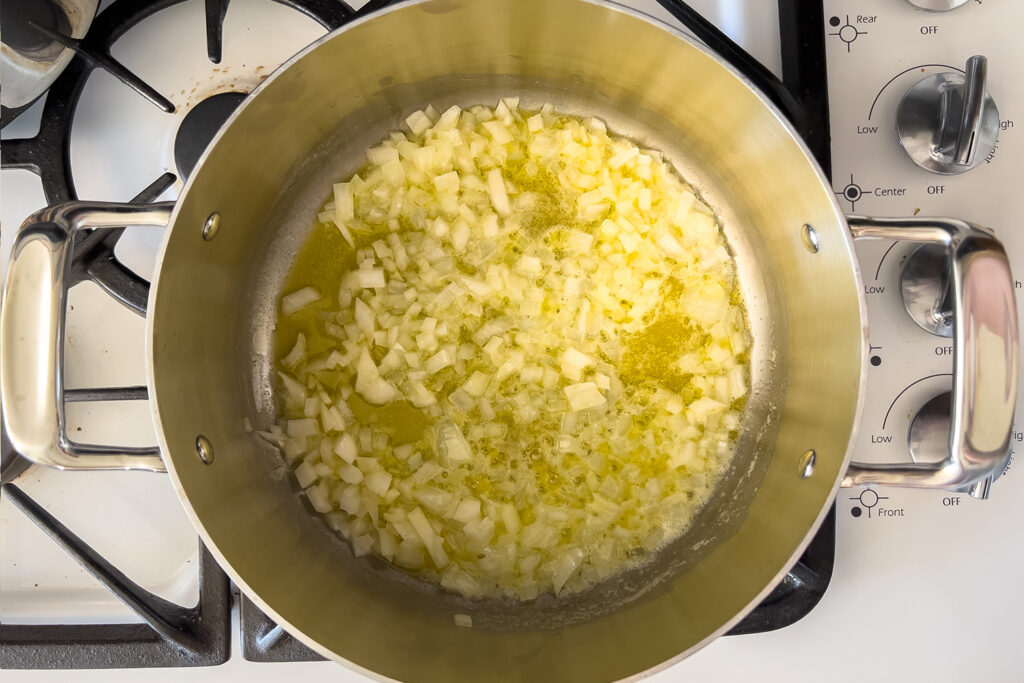 onions are cooking in butter in a pot on the stove