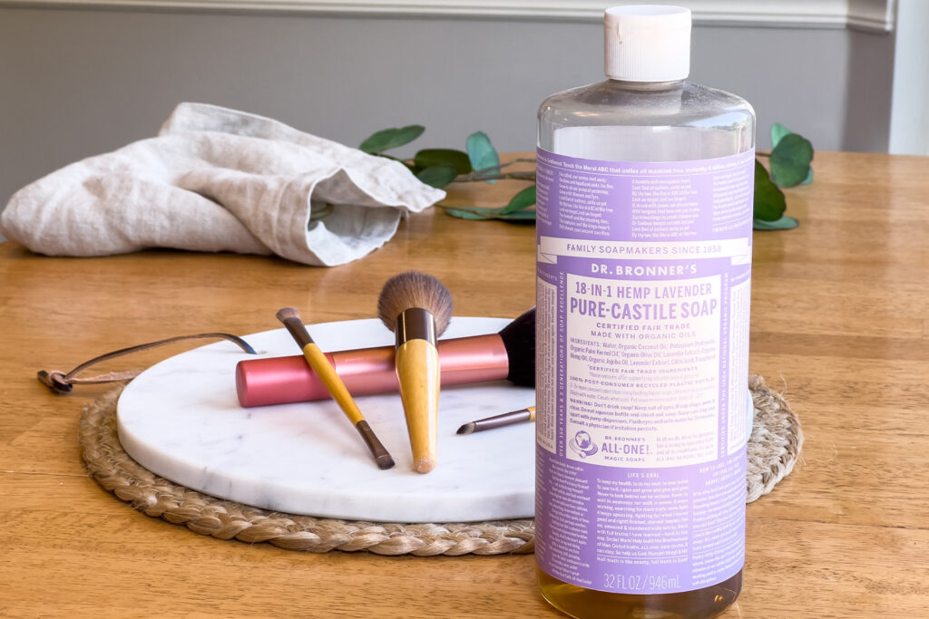 a bottle of Castile soap sits next to makeup brushes