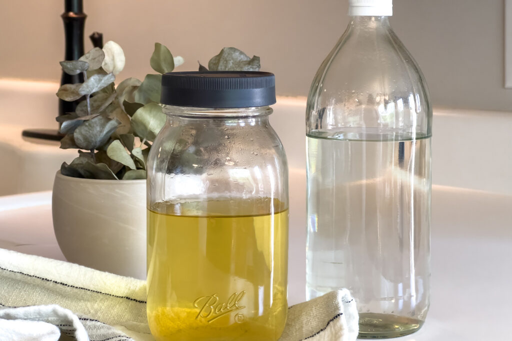 two jars of vinegar sit next to the kitchen sink