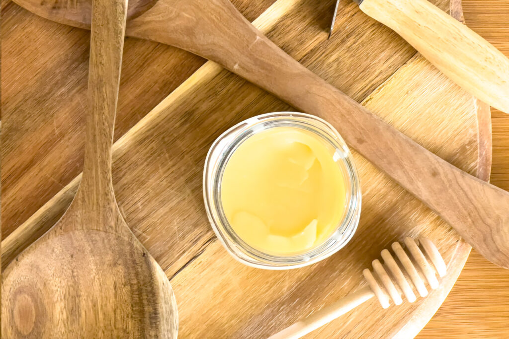 a jar of organic cutting board finish on a wood board with utensils