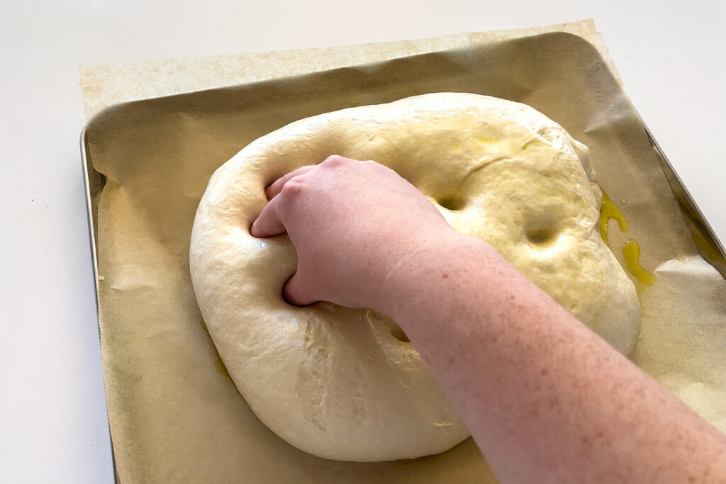 woman dimpling dough for sourdough focaccia