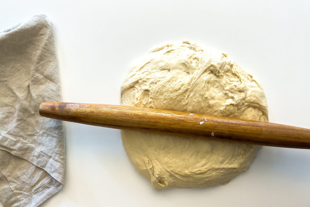 sourdough cinnamon roll dough being rolled out