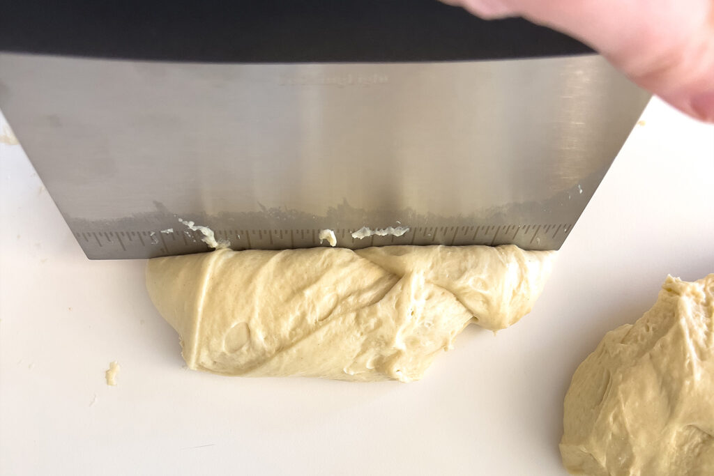 a woman dividing dough with a pastry cutter