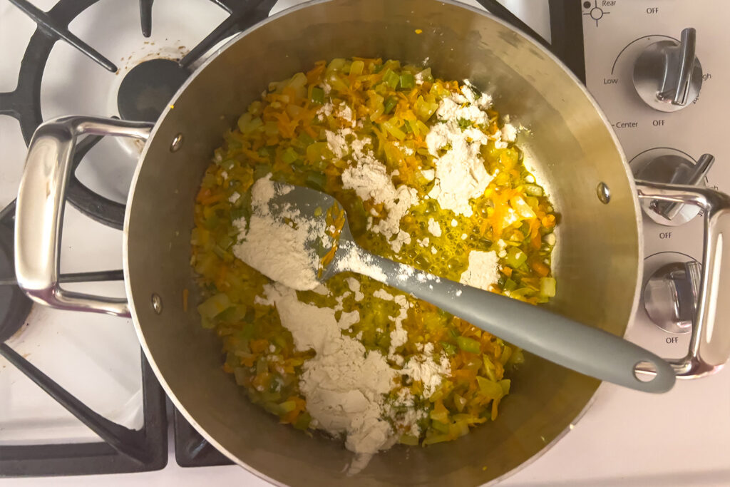flour sprinkled onto vegetables in a pot