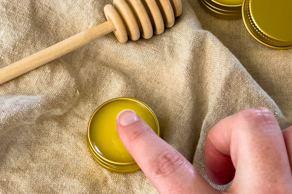 dipping a finger in beeswax lip balm