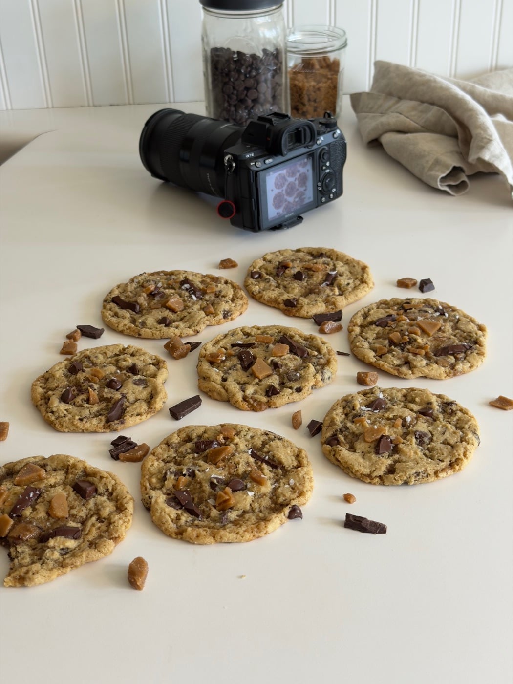 Behind the scenes: sourdough toffee chocolate chip cookies staged for a photo with a camera nearby