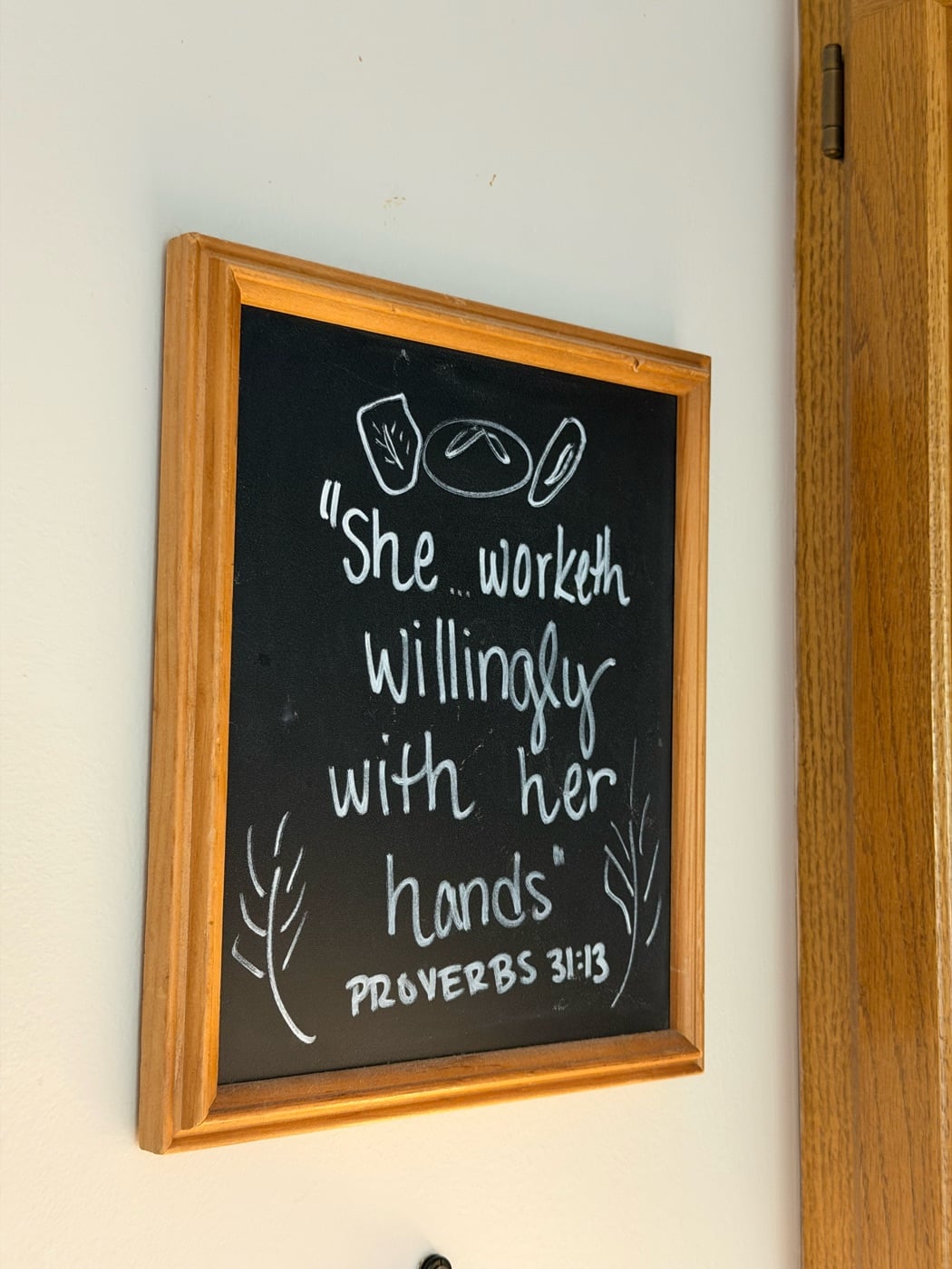 A hand-lettered chalkboard on Marlene’s kitchen wall with Proverbs 31:13: “She… worketh willingly with her hands”